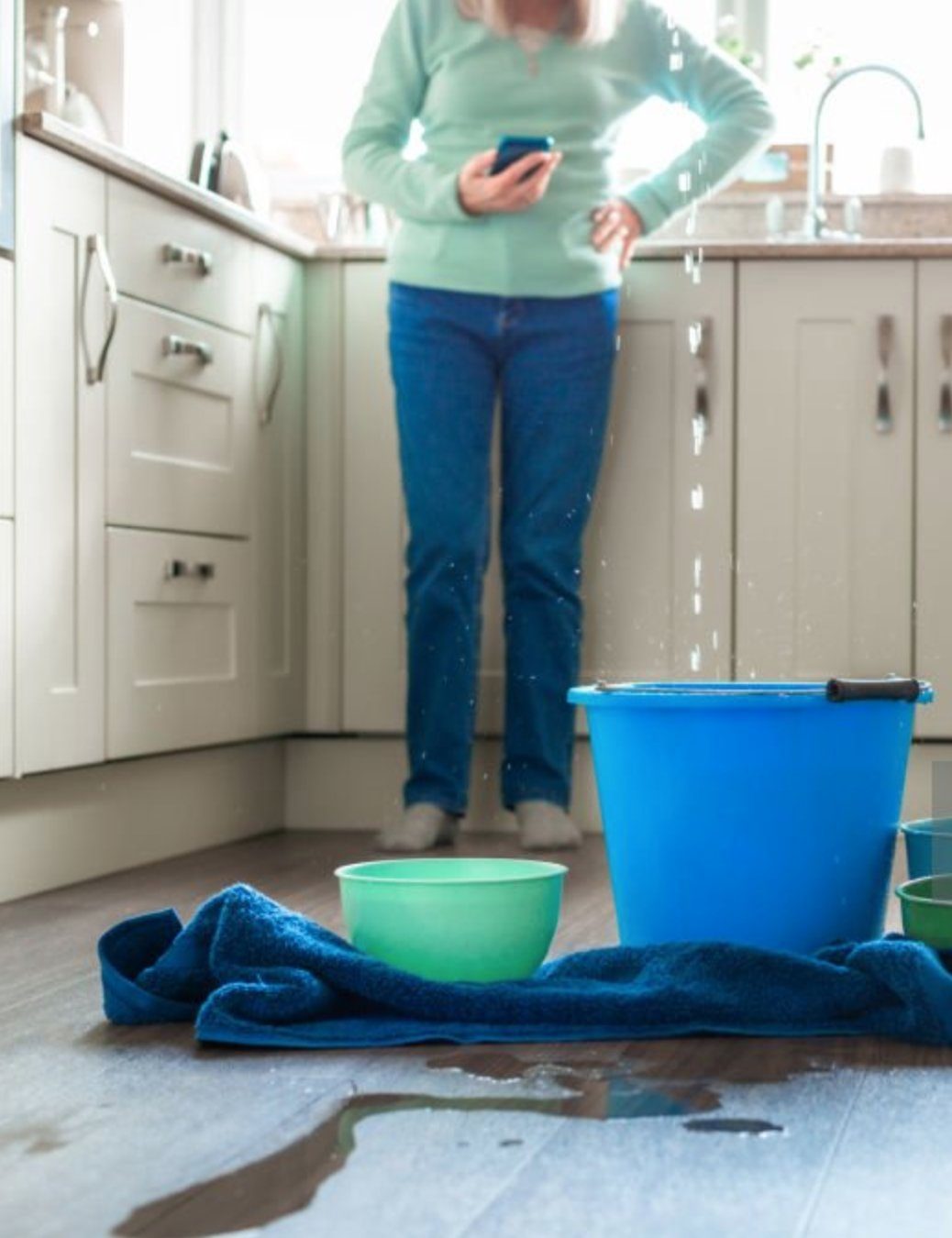 Water dripping from a kitchen cabinet into buckets — a hidden leak